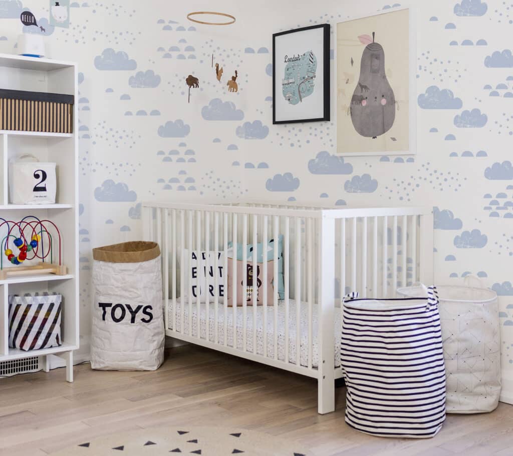 Nursery with blue cloudy sky wallpaper and playful decor.