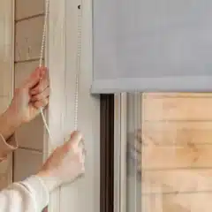 Close-up of a grey blockout fabric roller blind being adjusted with a chain.
