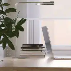 Modern workspace with sheer fabric roller blind, laptop, and books on desk.