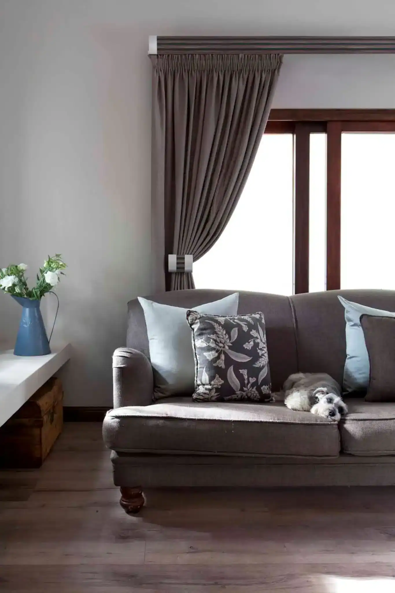 Elegant living room with taupe curtains and a cozy sofa with decorative pillows.
