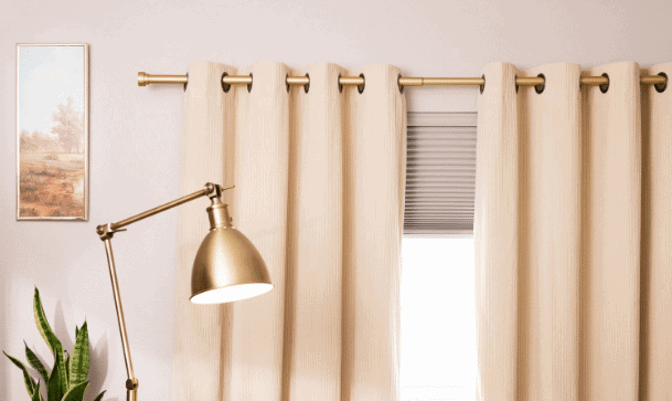 Elegant beige curtains with gold curtain rod in a modern living room.
