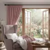 Cozy bedroom with open window overlooking a garden of pink and white roses.
